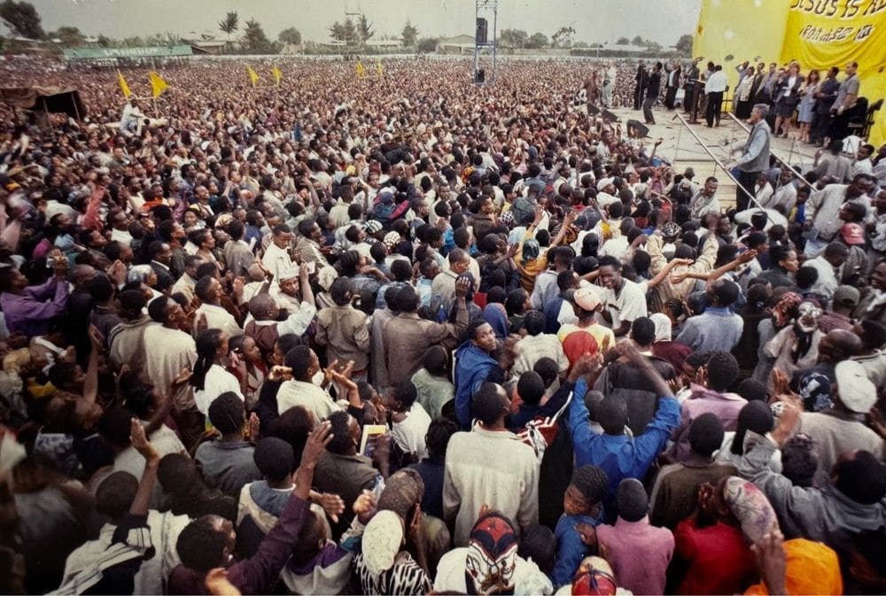 An older crusade crowd raising hands before the stage