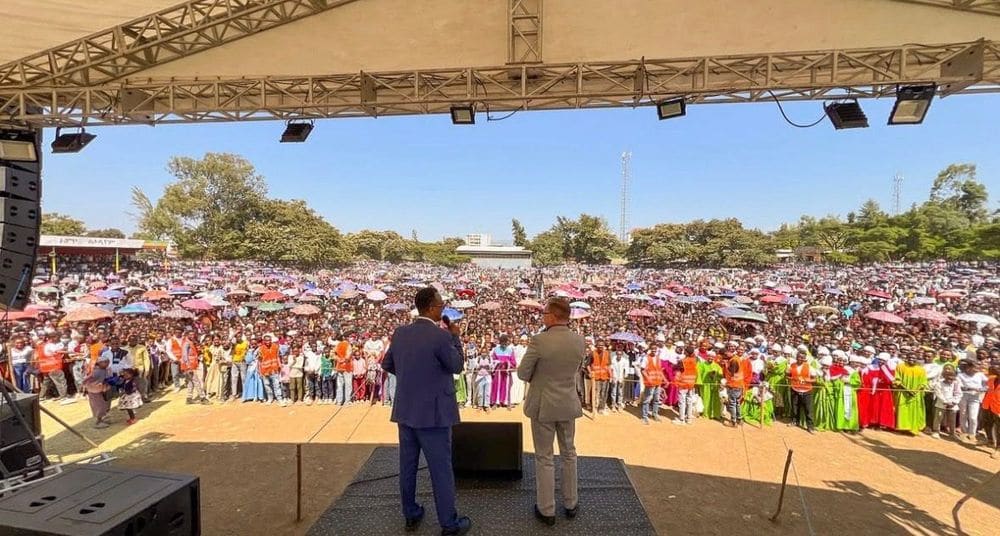 A historic crowd with colorful umbrellas seen from the campaign stage