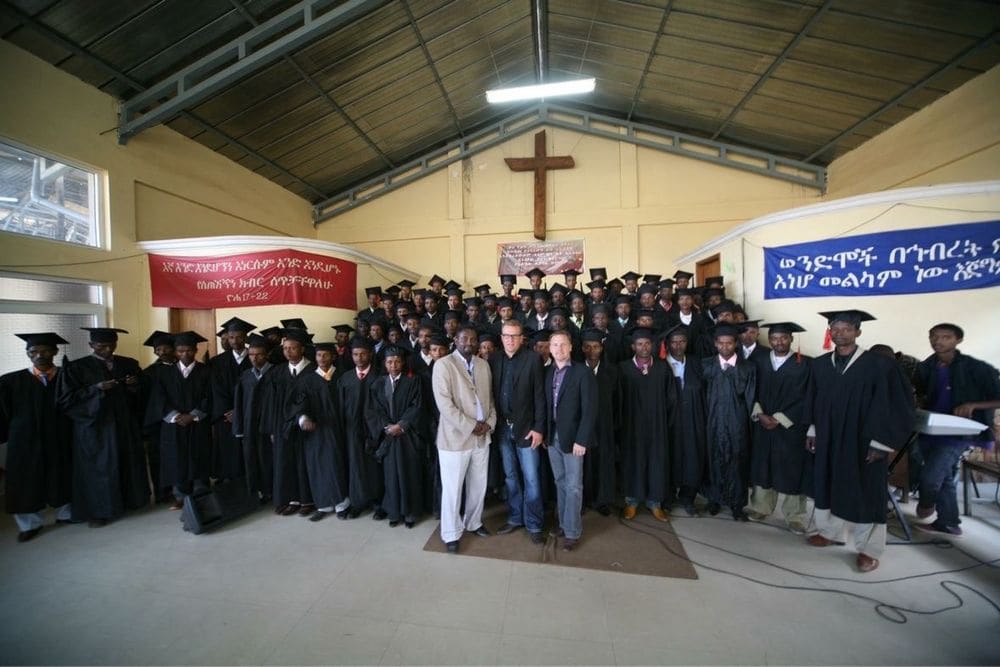 Karl Härgestam standing with a graduation group inside a church beneath a wooden cross