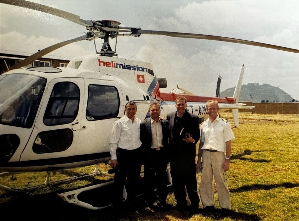 Karl Härgestam and three team members standing in front of a Helimission helicopter