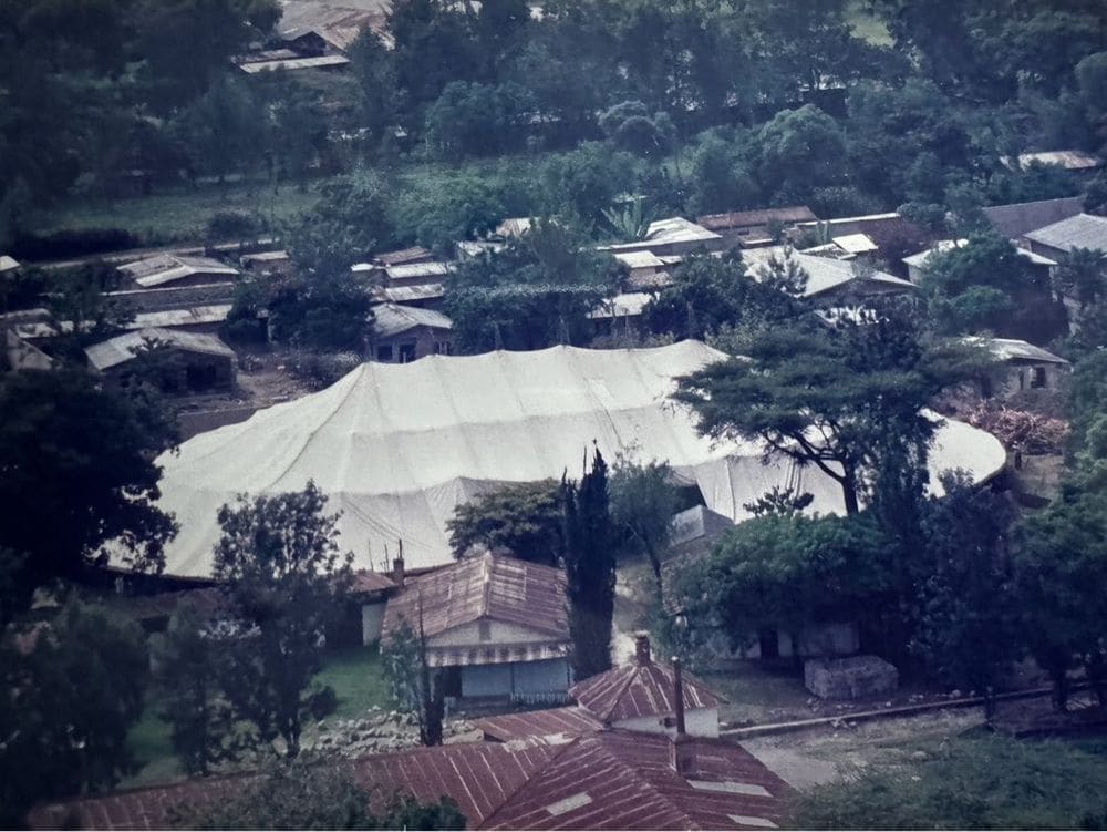 A second aerial angle of the large white campaign tent and surrounding village