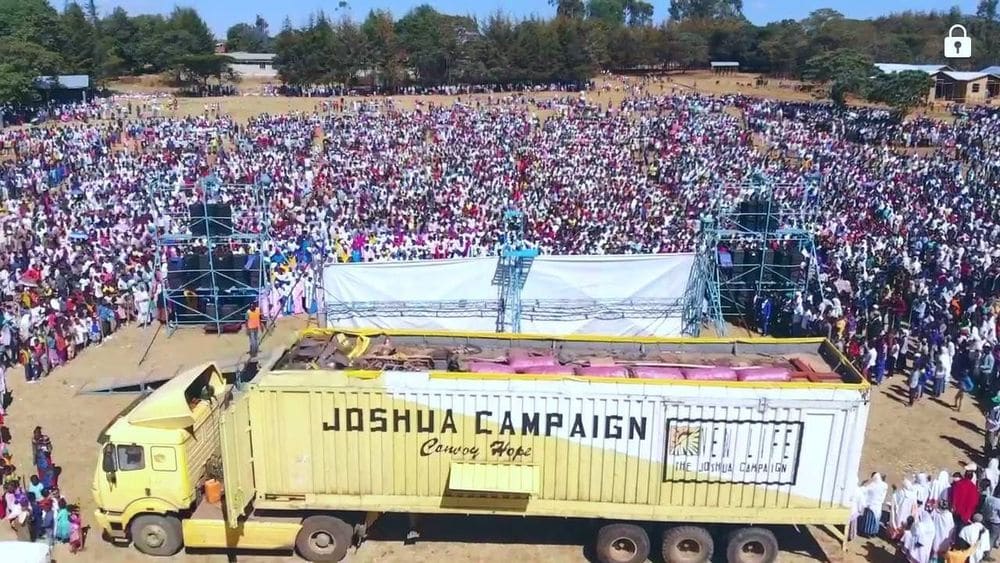 A later Joshua Campaign sound-stage truck positioned beside a large campaign crowd